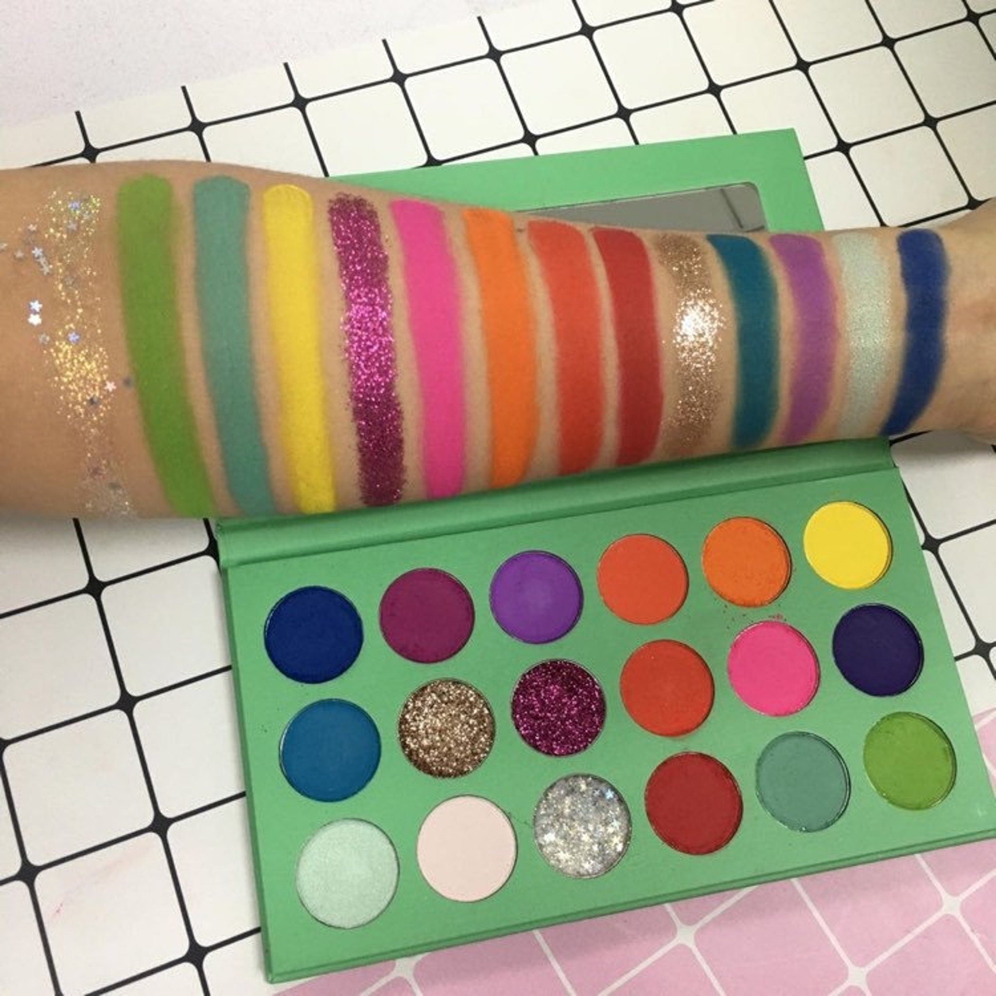 Eye shadow palette with green, pink, and glitter shades, shown on arm and in palette form