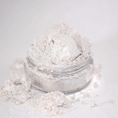 Glitter powder in a clear jar, silver and white, with spilled powder around it