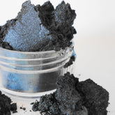 Eye shadow, dark navy blue mineral powder, in a clear jar with loose powder visible