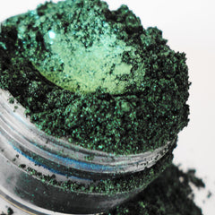 Green eyeshadow powder with glitter and clear jar, close-up view