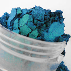 Blue powder pigment with teal highlights in a clear glass container