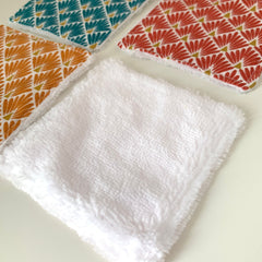 Elegant stack of reusable bamboo makeup wipes and cotton squares with natural texture on marble surface