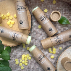 Lip balm tubes in brown paper, with yellow balm, and KAAZY brand text on surface
