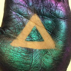 Iridescent textured surface with teal, purple, and yellow triangle shape on hand