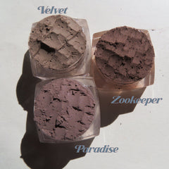 Side view of six matte brown loose mineral eyeshadows in round jars with black lids, showcasing texture and vegan labeling.