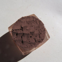 Close-up of dark matte brown mineral eye shadow powder with smooth velvety texture in open container