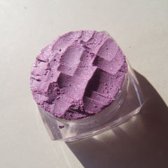 Purple eyeshadow with glitter, textured powder in clear plastic container