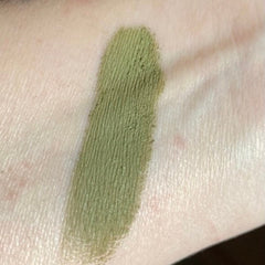Green eyeshadow swatch on skin, showing textured application and olive color