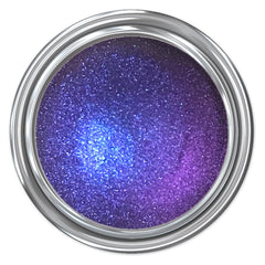 Close-up of Voodoo Dolly multichrome eyeshadow pan showing shifting iridescent purple and green hues with smooth metallic finish