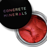 Eyeshadow product with red powder, silver rim, and black lid with Concrete Minerals text
