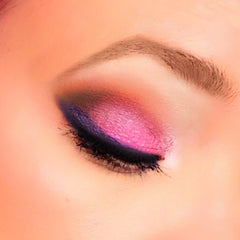 Eye makeup with pink, purple, and black eyeshadow, applied on a closed eye, with a brown eyebrow visible