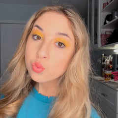 Close-up of a makeup brush applying shimmering bronze eye shadow to eyelid