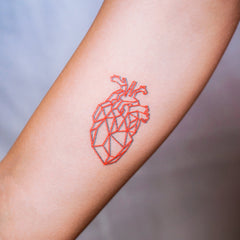 Close-up of a skin-friendly red geometric heart tattoo sticker applied on wrist with clean, precise edges