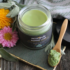 Clay cleanser jar with green paste, wooden spoon, and Mama's Garden label on black background
