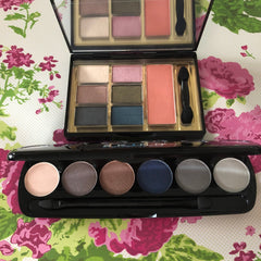 Eyeshadow palettes with various colors and black applicator, on floral background
