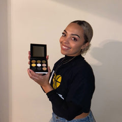 Close-up of a makeup brush applying shimmering black eye shadow to eyelid with blending motion