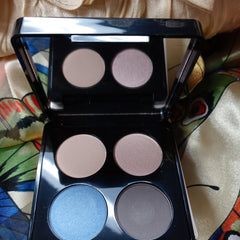 Eyeshadow palette with black case, matte and shimmer shades in blue, brown, and nude colors, with mirror