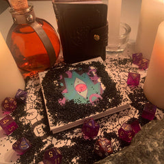 D&D Warlock Eyeshadow Palette featuring 12 matte and shimmer shades in deep purples, blues, and neutrals with gold detailing.