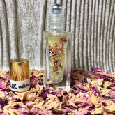 Lip balm bottle with clear glass, gold cap, and floral accents, "B.L.K. natural" label visible