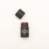 Tinted lip balm, black paper tube with coral balm, "lips" text visible