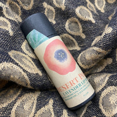 Lip balm tube with black cap, beige label, and floral design on patterned fabric