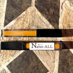Lip gloss tubes with yellow liquid and black caps, "bare Natur-ALL" label on stone surface