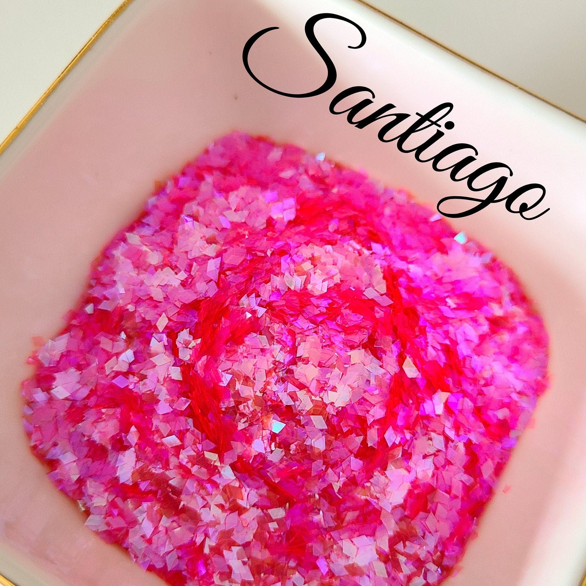 Loose glitter eyeshadow, pink holographic glitter, in a pink dish, with "Santiago" text