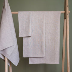 Linen towels in light grey with a textured weave hanging on a wooden rack
