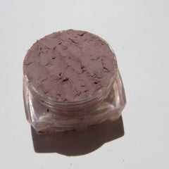 Close-up of matte taupe brown loose mineral eyeshadow with fine powder texture in eco-friendly packaging