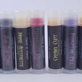 Lip balm tubes with clear caps, dark labels, and various colors including red and purple, Badass Apothecary brand