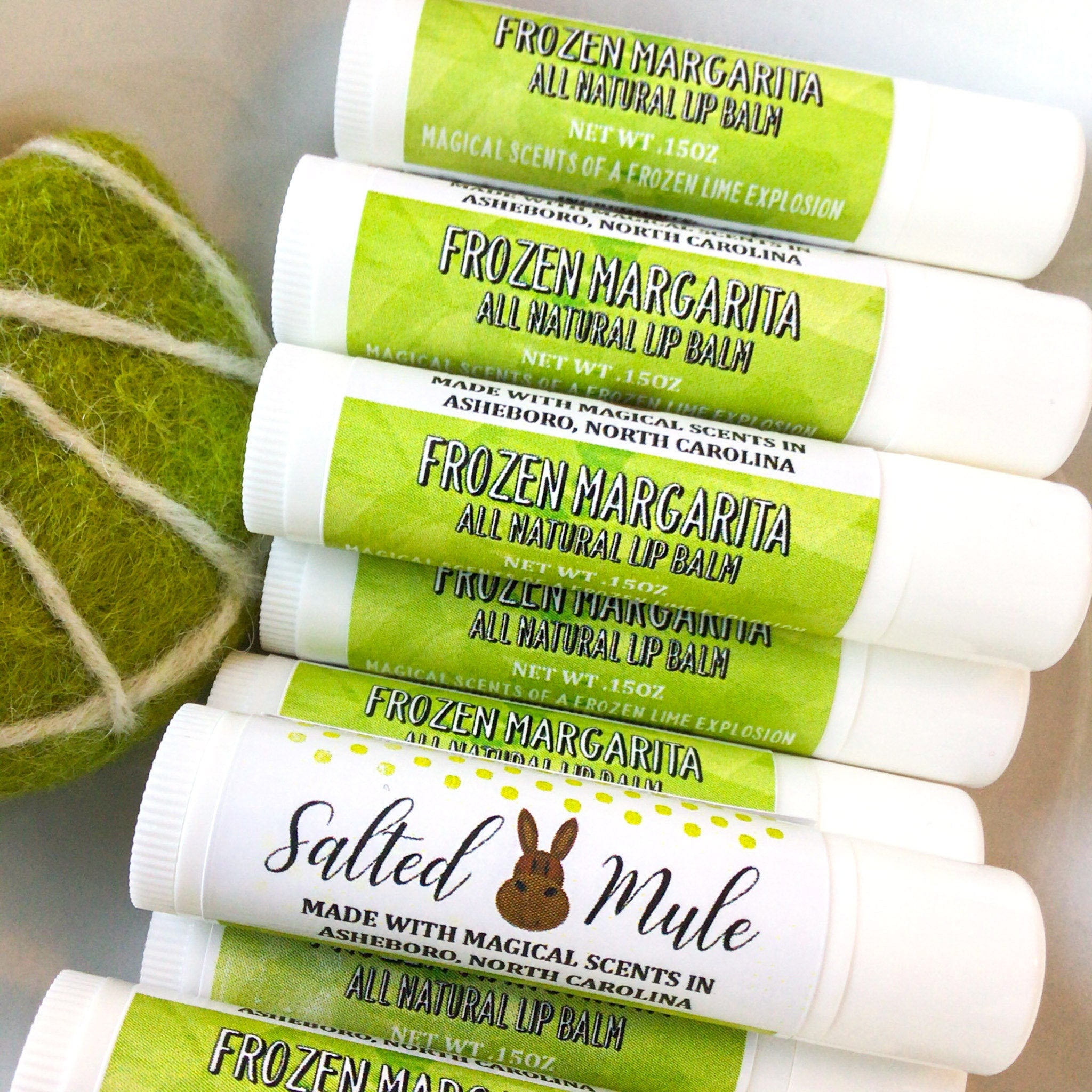Lip balms with white tubes, green labels, and Salted Mule branding stacked together