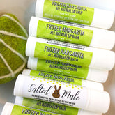 Lip balms with white tubes, green labels, and Salted Mule branding stacked together