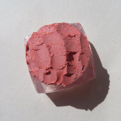 Hand applying sunset orange shimmer vegan eyeshadow with brush, showcasing loose pigment blendability on skin