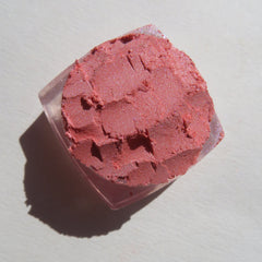 Side view of loose Sunset Orange shimmer eyeshadow in glass jar, showcasing vegan mineral pigment texture