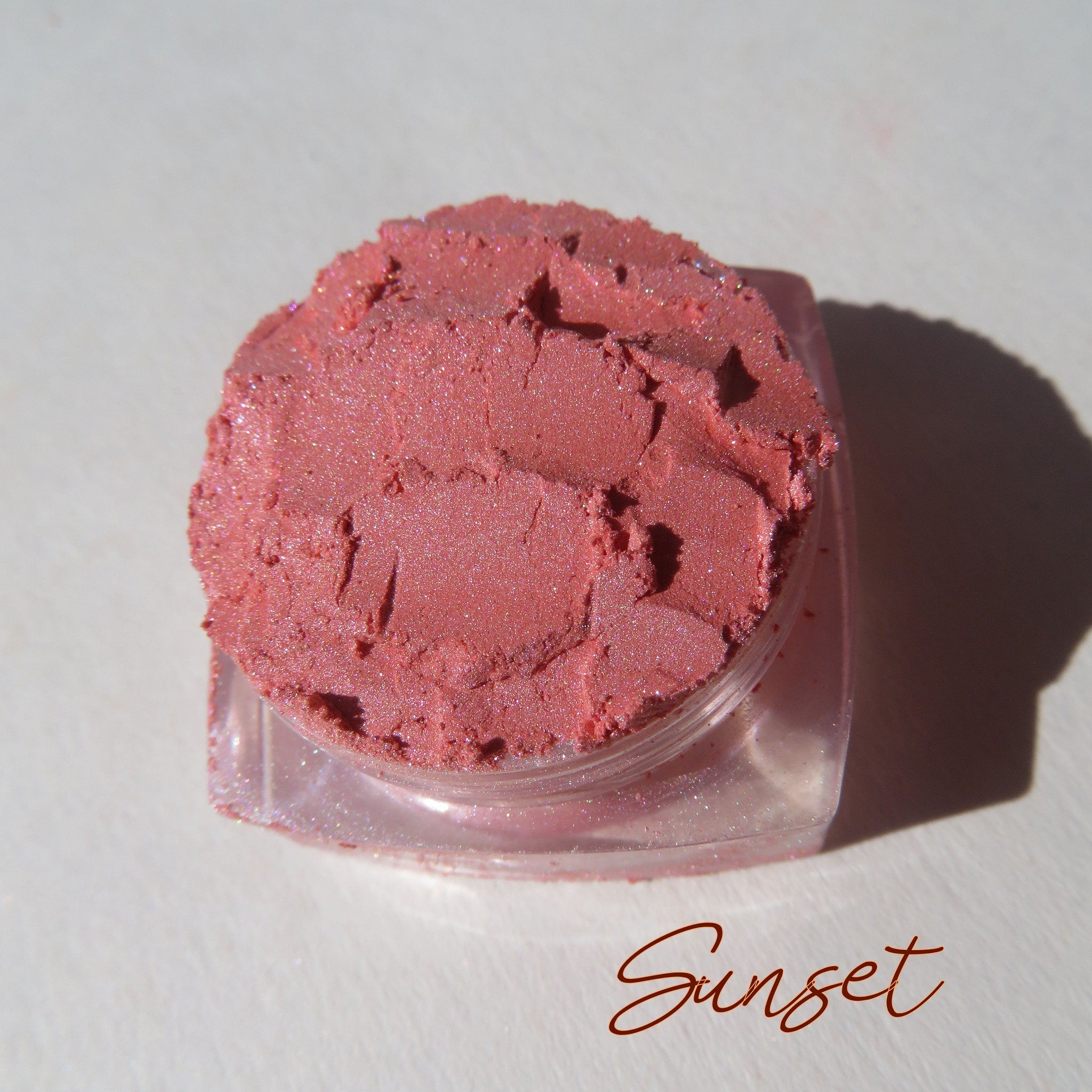 Sunset orange shimmer loose mineral eyeshadow in a round black jar with gold lid, cruelty-free vegan makeup.