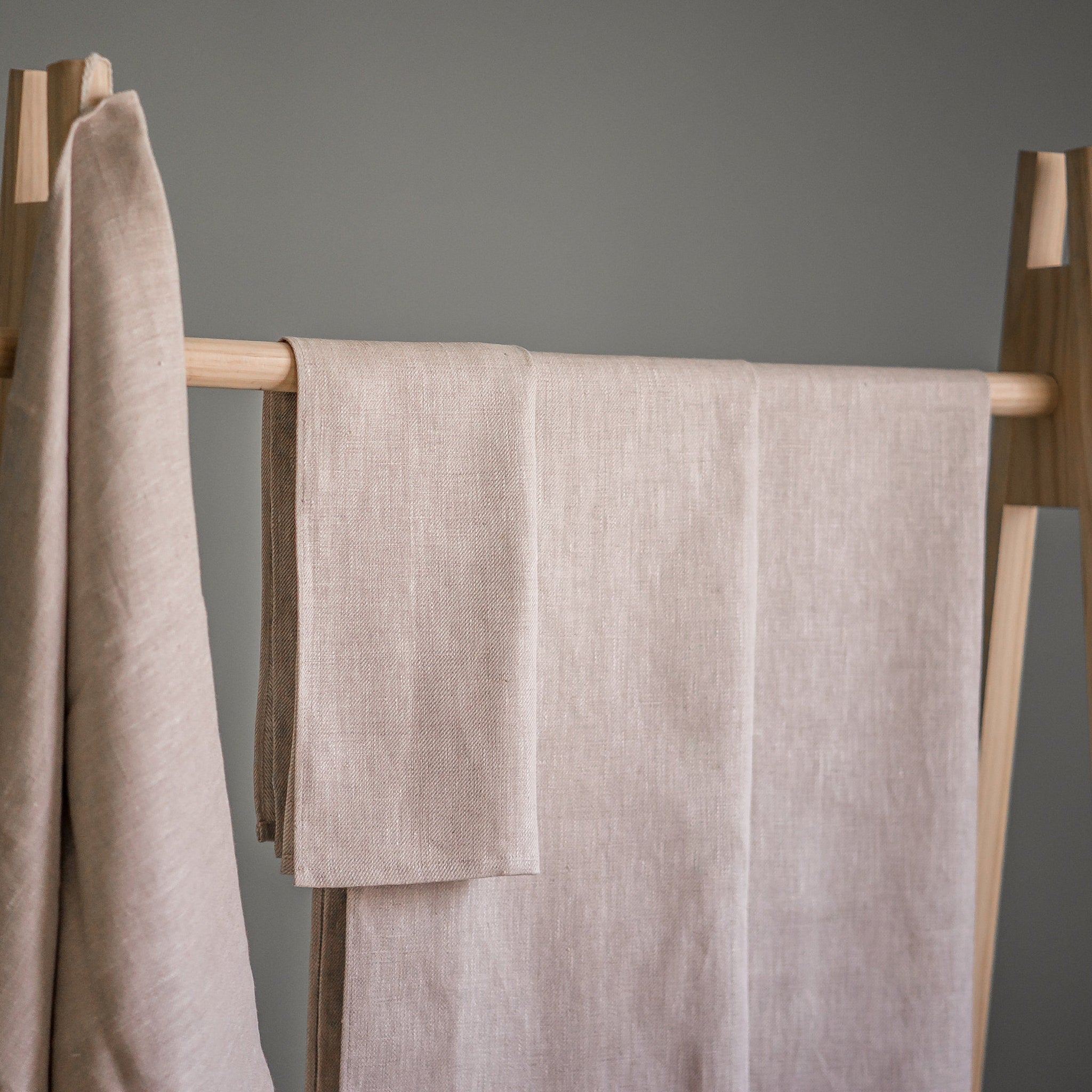 Beach towels, beige linen, folded on wooden rack, Alma Linum brand