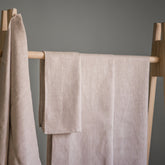 Beach towels, beige linen, folded on wooden rack, Alma Linum brand