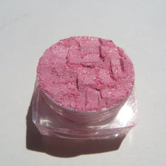 Pink glitter eyeshadow powder in clear plastic jar, textured surface, sparkling particles