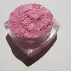 Pink eyeshadow with glitter and a clear plastic container, close-up shot