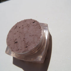 Hand applying matte taupe brown mineral eye shadow with brush for a soft, blended look on eyelid