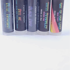 Lip balm tubes with black, iridescent text, and white base, various flavors visible