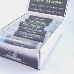 Lip balm tubes with blue and black labels in a white box, "BLUE HAWAIIAN" text visible