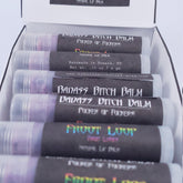 Lip balms in clear tubes with black labels, Badass Apothecary text visible, packaged in box