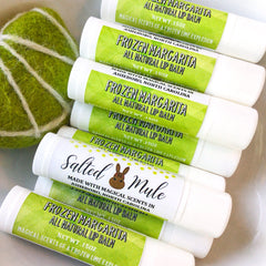 Lip balm tubes with white and green labels, text "Frozen Margarita" and "Salted Mule" visible
