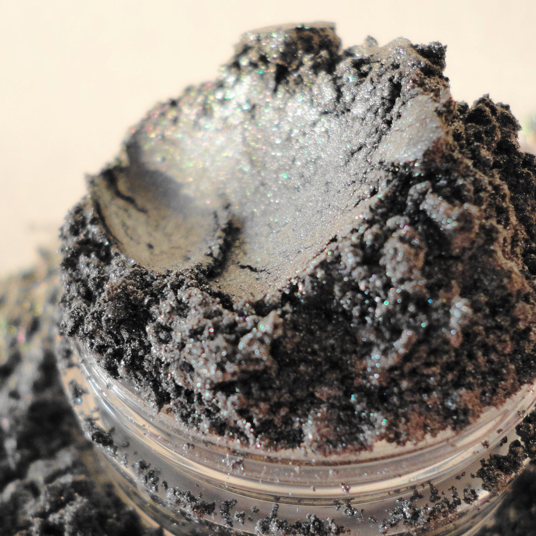 Eye shadow powder, gray-silver shimmer, in clear jar, close-up view