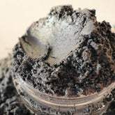 Eye shadow powder, gray-silver shimmer, in clear jar, close-up view