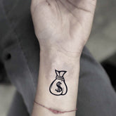 Two realistic money bag tattoo stickers with detailed shading, placed on clean skin for temporary cosmetic enhancement