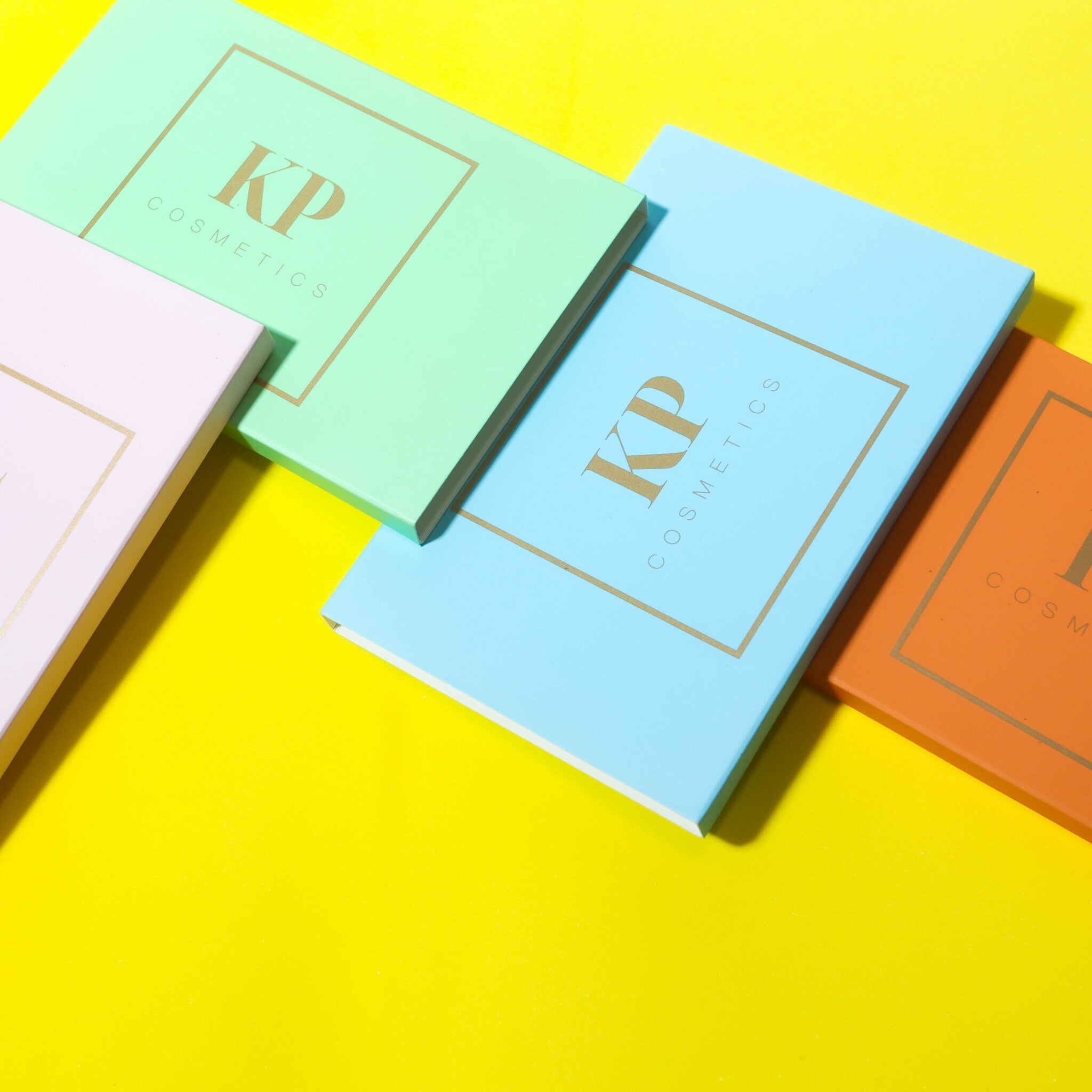 Assorted pressed powder eye shadows in shimmering neutrals and bold jewel tones with sleek black compact packaging