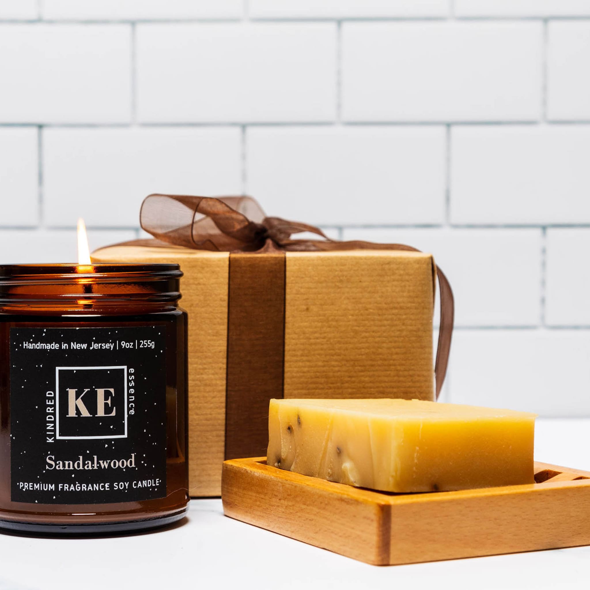Bath & body gift set with brown candle, gift box, and soap on wooden tray