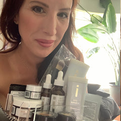 Skincare products in clear plastic case with white and brown bottles, held by woman